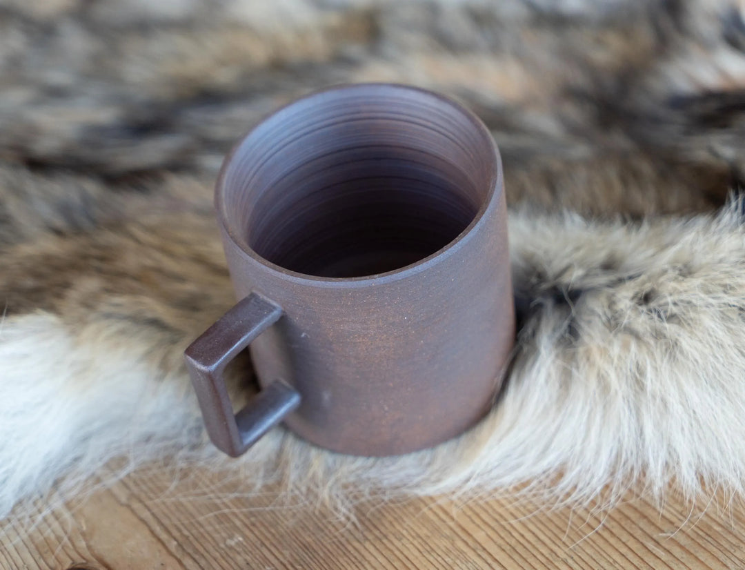 Stoneware espresso mug, light purple-gray, open top and side handle on faux-fur