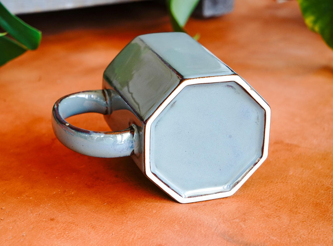Octagonal ceramic mug with handle, light blue interior and dark exterior glaze