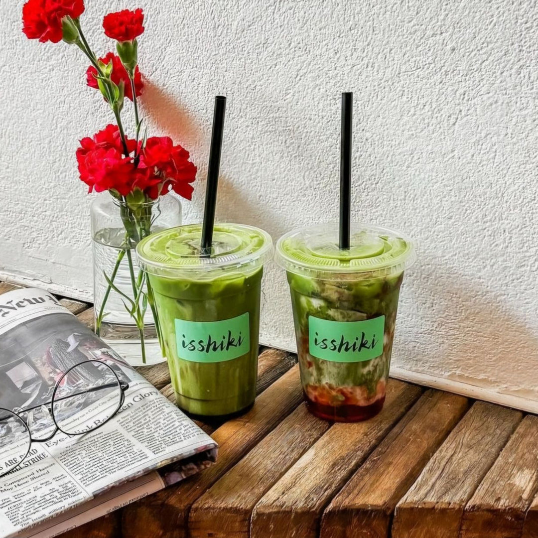 Two iced green matcha cups with black straws and ice, “isshiki” labels