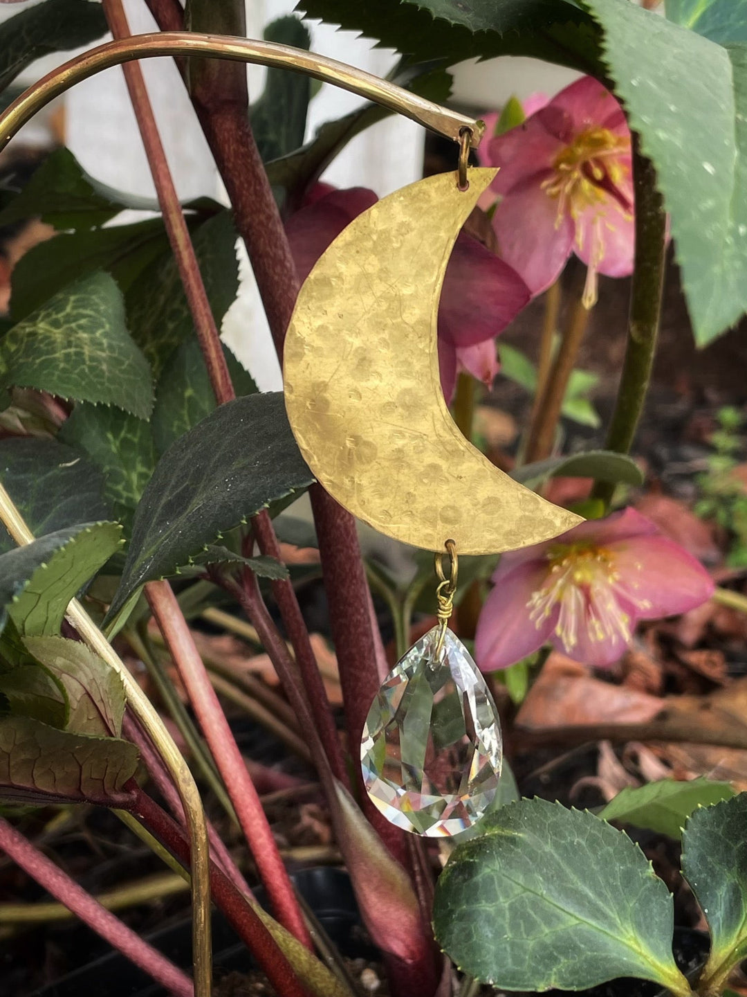 Gold crescent moon suncatcher with clear crystal teardrop hanging among flowers