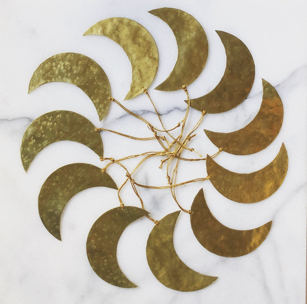 Gold crescent-moon ornament featuring layered crescent shapes with thin dangling strings