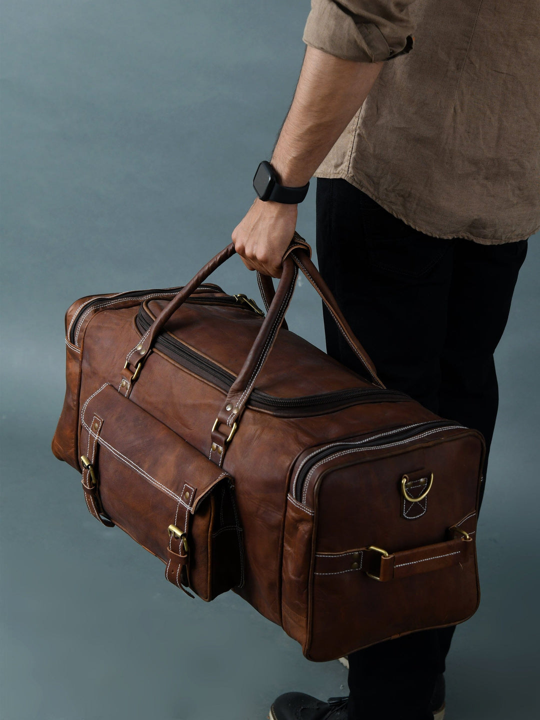 Brown leather weekender duffle bag with stitched panels, top handle and front buckle