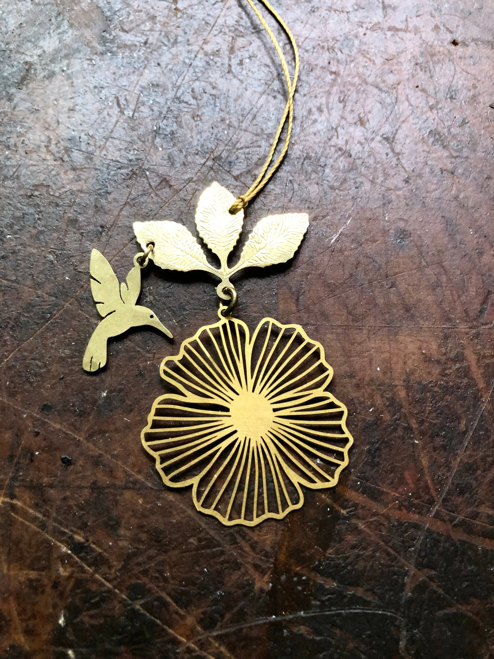 Gold hibiscus flower ornament with hummingbird and leaf charm, hanging string loop