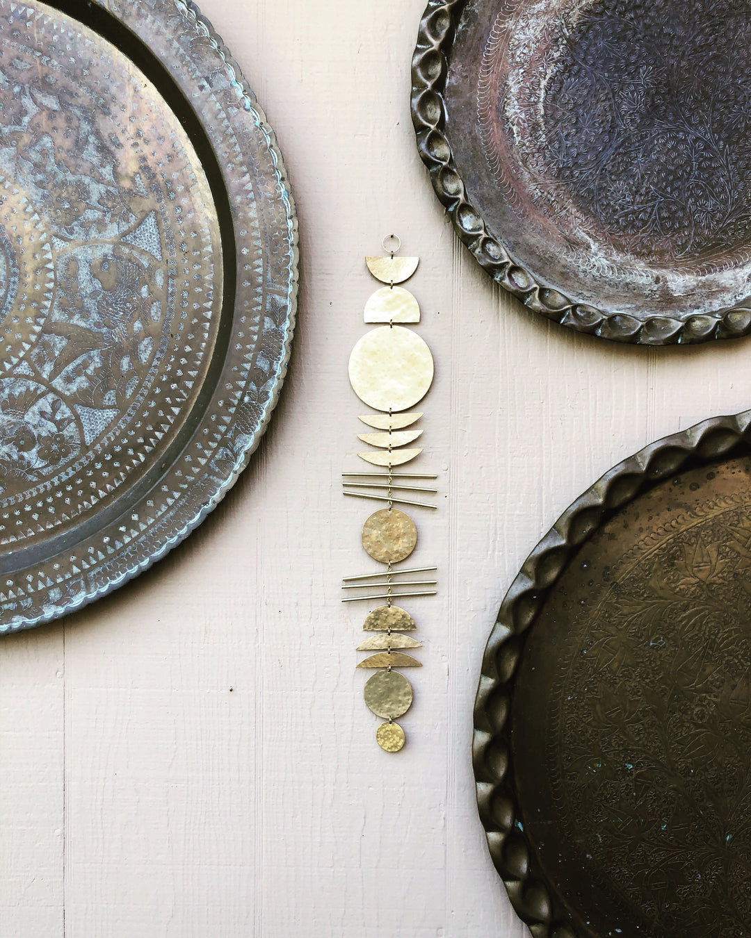 Gold-tone stacked metal disk wall ornament near blue patterned plates and a tray