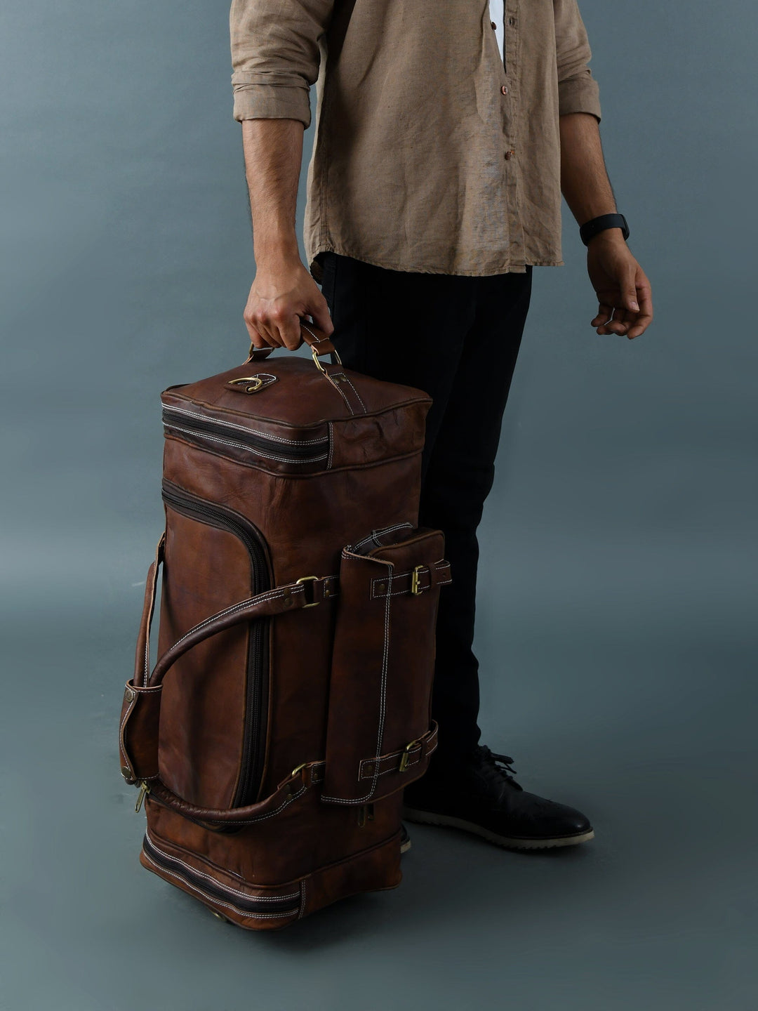 Brown leather weekender duffle bag upright, front zip compartment and buckled details