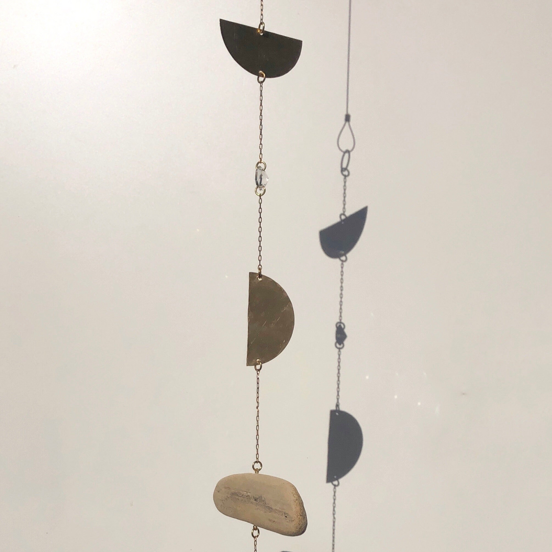 Hanging suncatcher with dark crescent metal pieces and beige stone accent