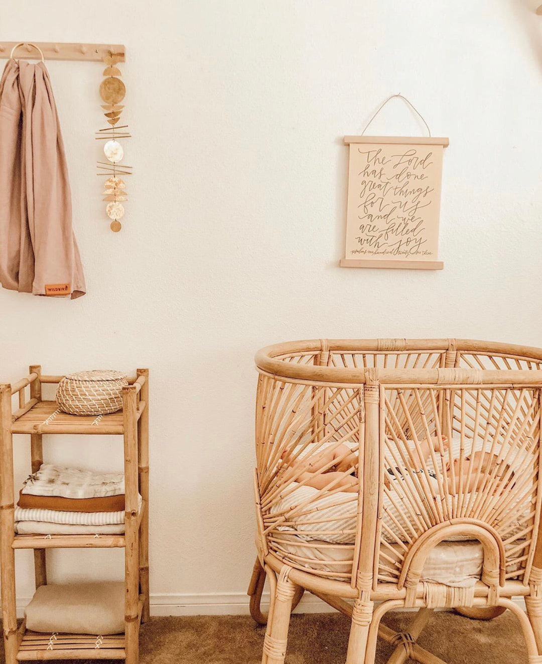 Gold-tone disk wall hanging on a light wall near a rattan chair and shelf decor