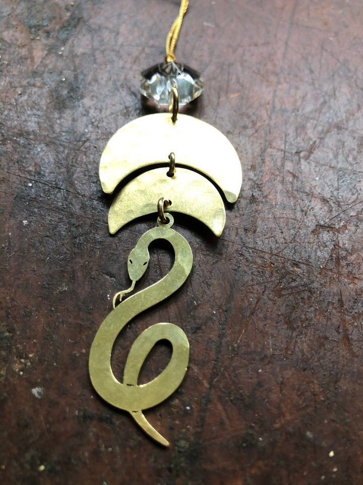 Gold serpentine ornament with clear glass crystal top, hanging on a cord
