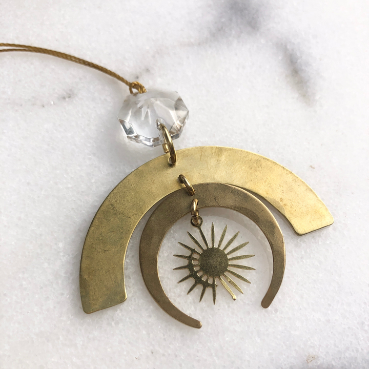 Gold-tone crescent ornament with vintage clear glass crystal and sunburst center.