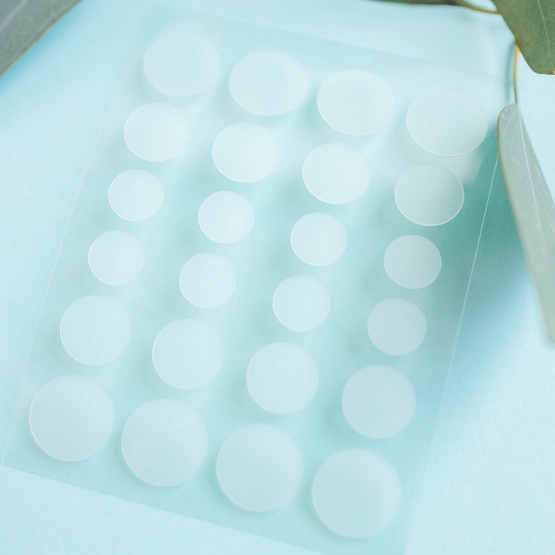 Sheet of white round hydrocolloid healing patches with peelable circles.