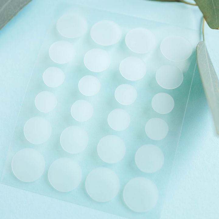 Sheet of white round hydrocolloid healing patches with peelable circles.