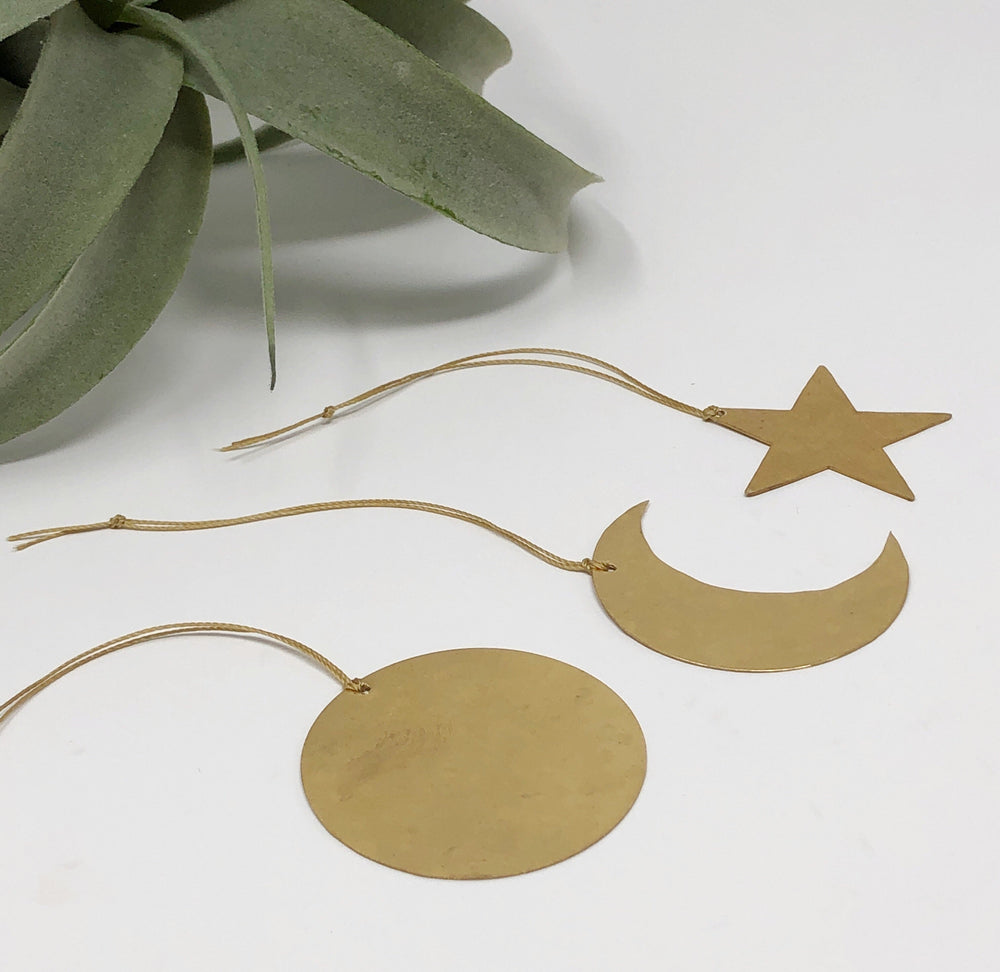 Celestial ornament set with gold shapes: star, crescent moon, and round disk on cords