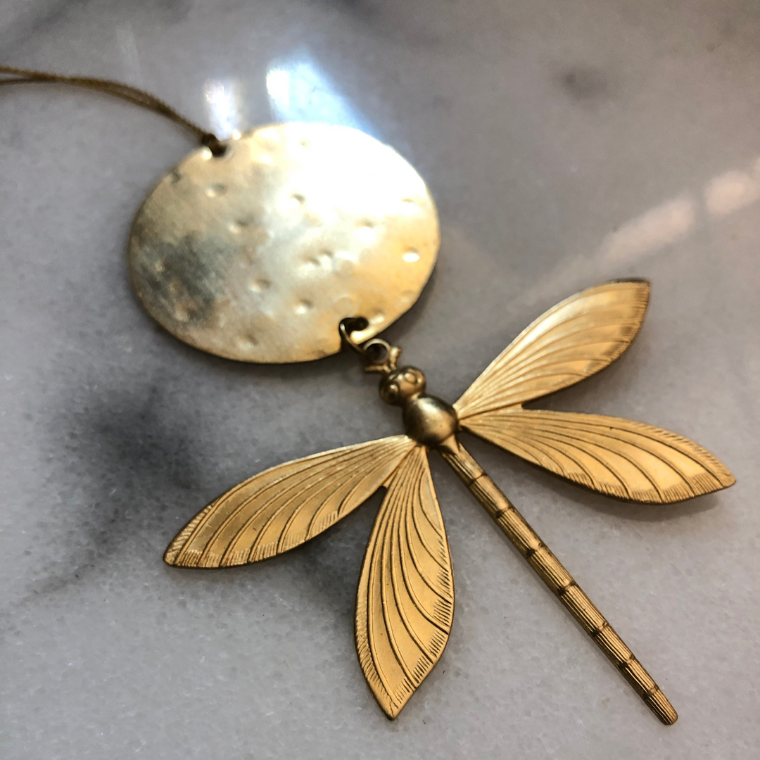 Gold-tone dragonfly ornament with round tag and textured wings, hanging on a loop.