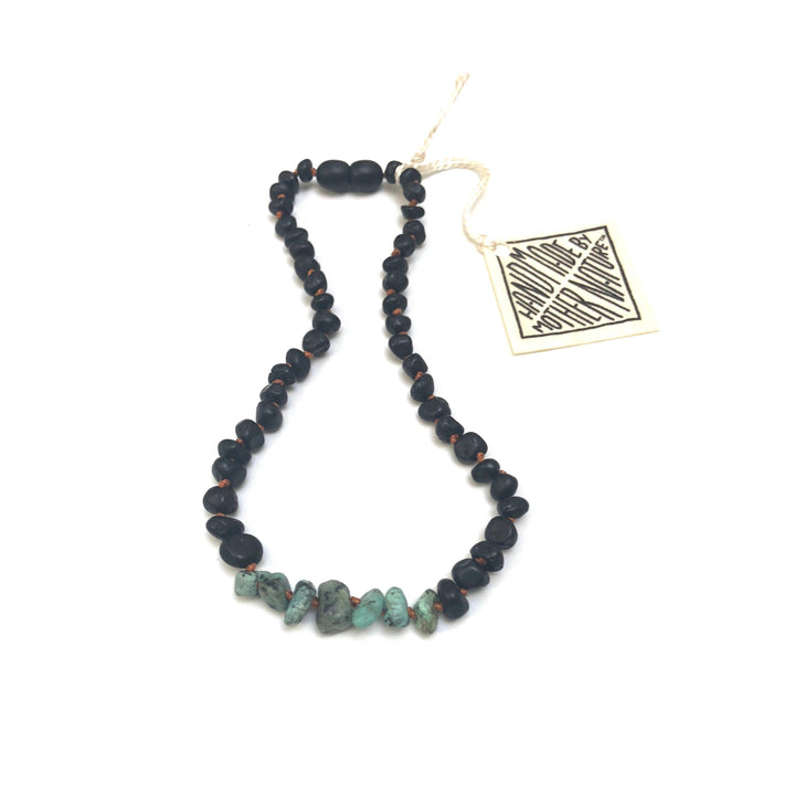 Black beaded necklace with irregular turquoise stone segments and a hanging tag