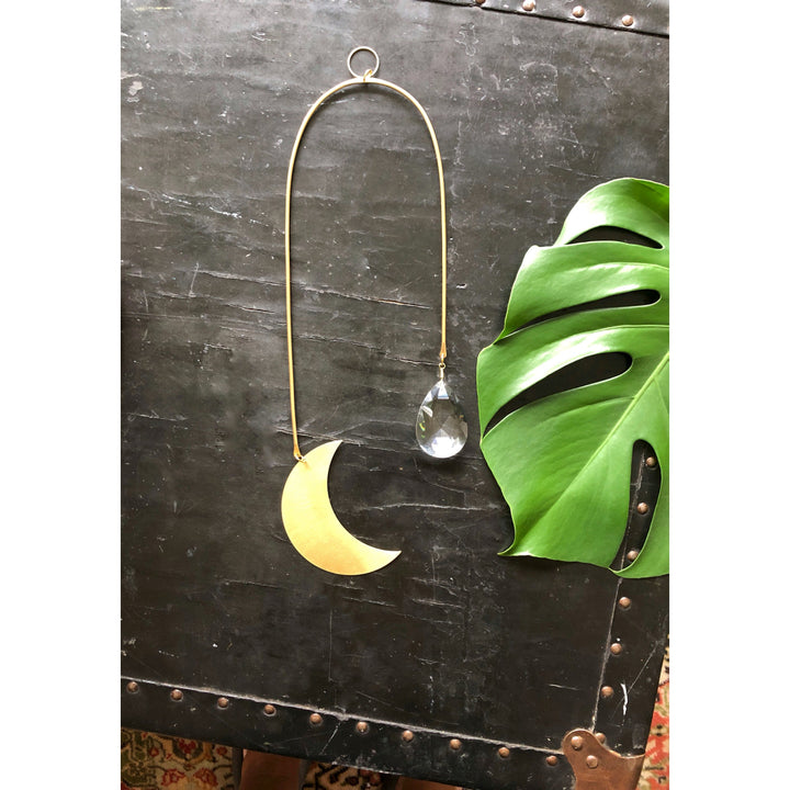 Moon-shaped metal suncatcher with dangling clear crystal teardrop charm.