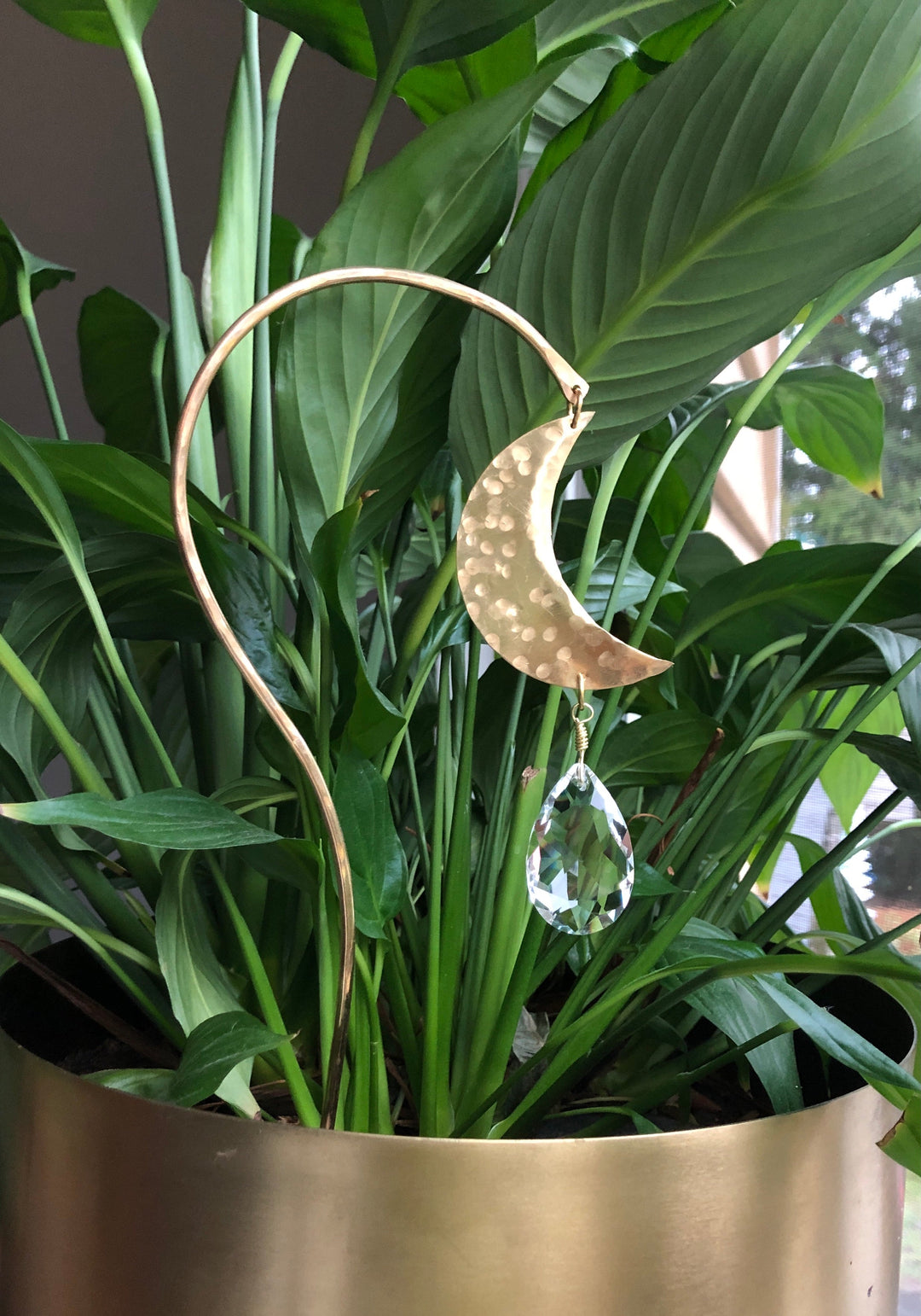 Gold crescent moon and clear crystal teardrop suncatcher hanging in plant leaves