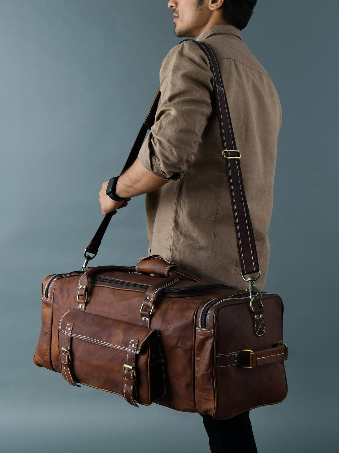 Brown leather duffel bag carried by child with adjustable crossbody strap