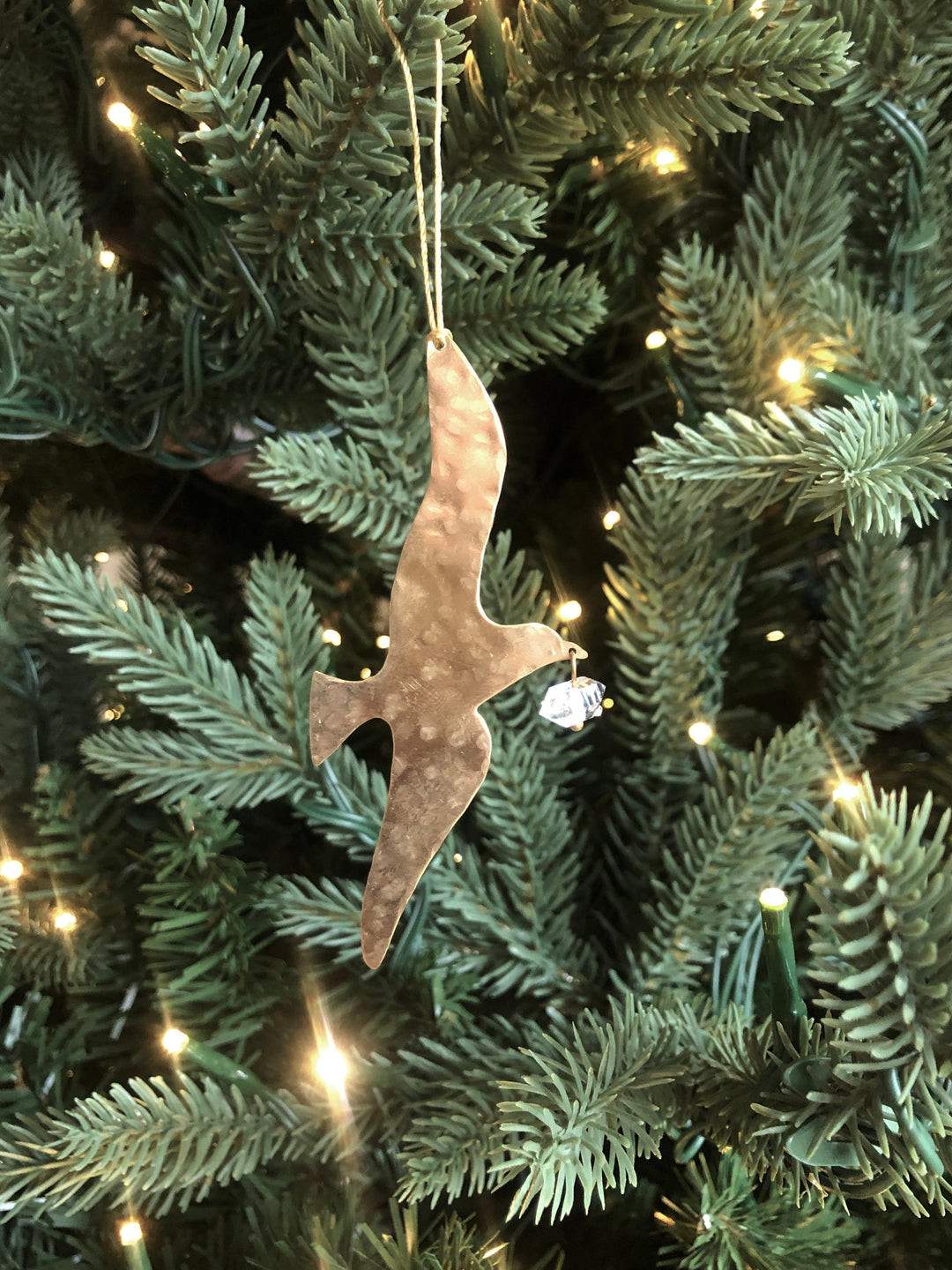Gold-toned hammered ornament with clear Herkimer diamond, hanging from tree branch