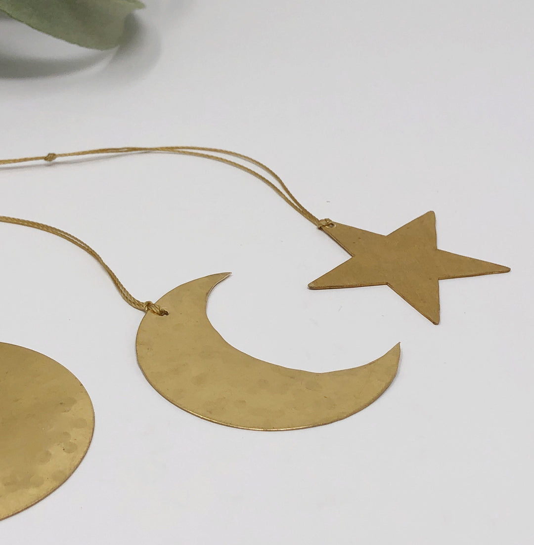 Gold crescent moon and star ornaments with thin hanging cords on a clean background
