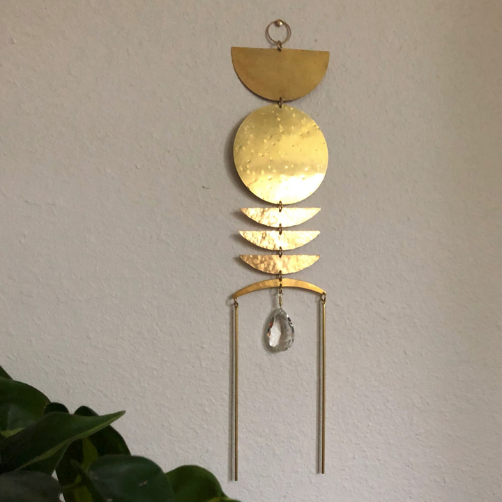 Gold sun catcher with stacked crescent discs and hanging crystal teardrop charm