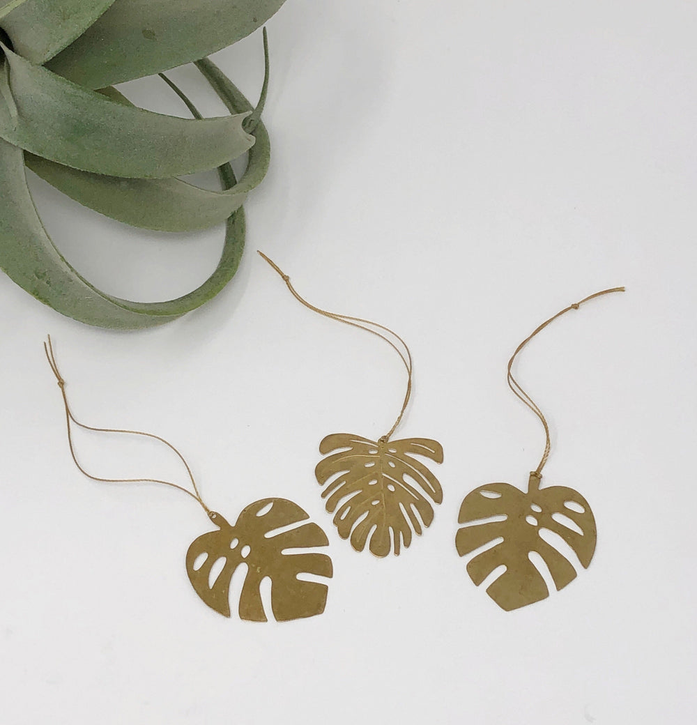 Gold leaf ornament garland with three monstera-shaped cutouts on string cords
