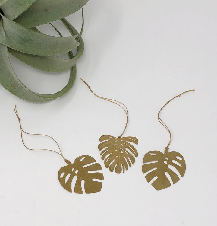 Gold leaf ornament garland with three monstera-shaped cutouts on string cords