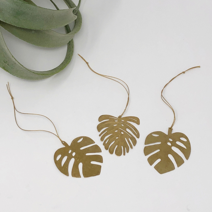 Gold monstera leaf ornaments on thin string cords, three-leaf garland