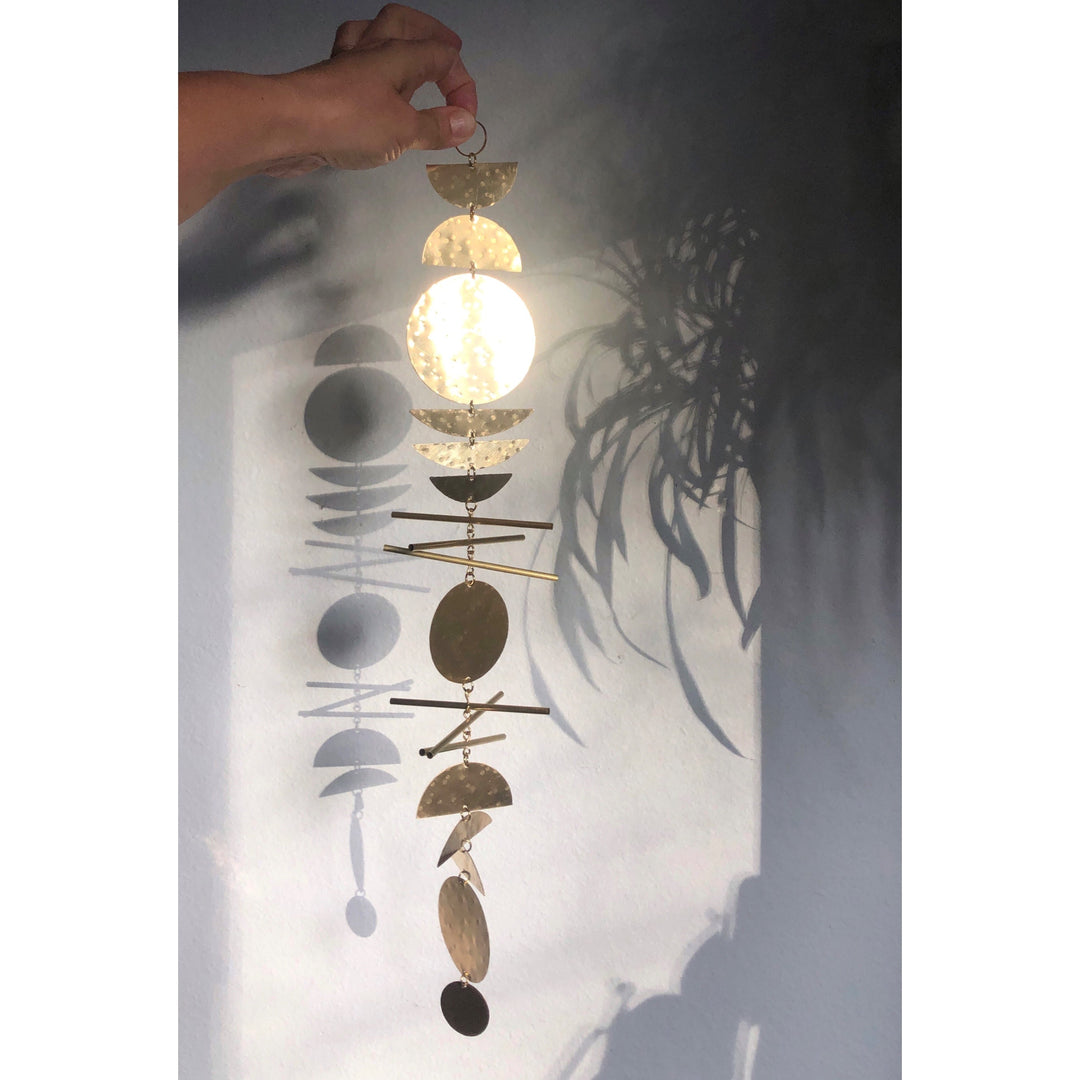Gold-tone metal wall hanging with stacked circular disks and small dangling charms