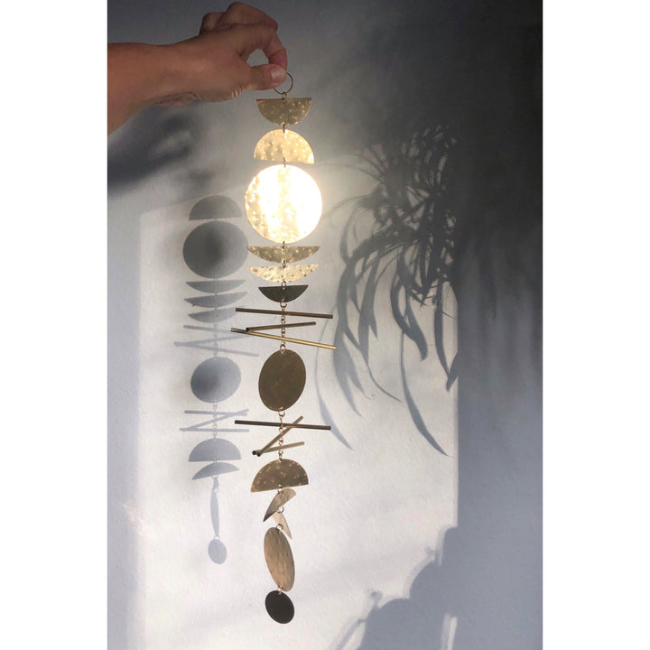 Gold-tone metal wall hanging with stacked circular disks and small dangling charms