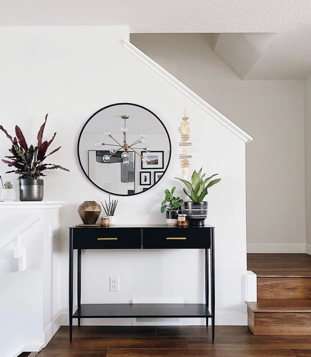 Gold-tone metal wall hanging with stacked circular disks above a console table
