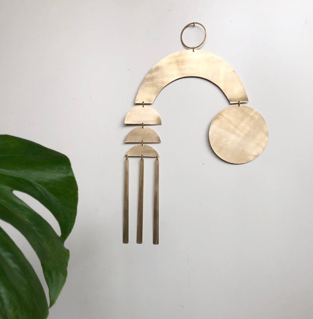 Beige wood arc wall hanging with layered crescents, round disc, and three hanging tassels.