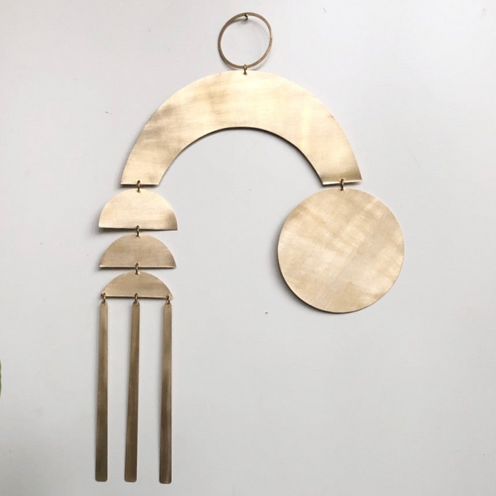 Beige wood arc wall hanging with round disc and three tassels on a metal ring.