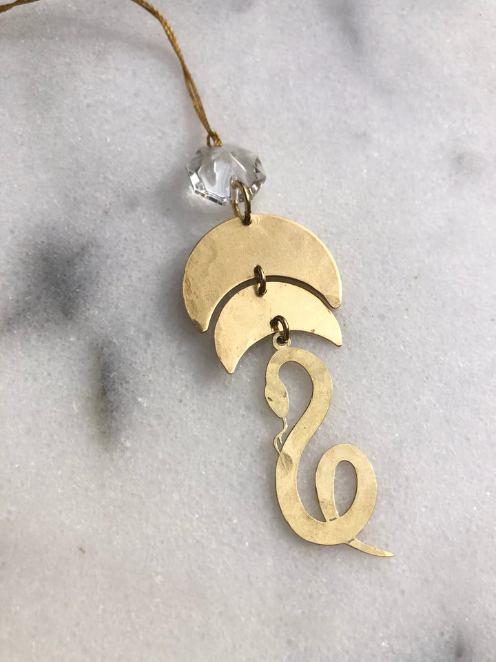 Gold serpentine ornament with clear glass crystal cap, viewed from upper angle