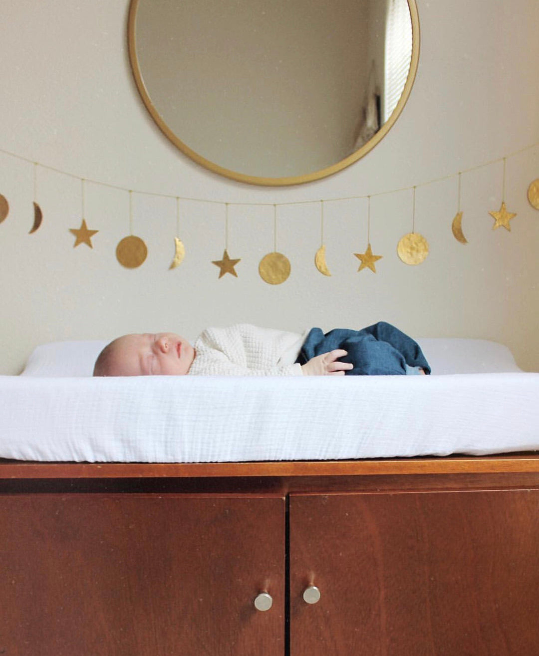Gold hammered star and crescent moon garland strung along a wall above a bed