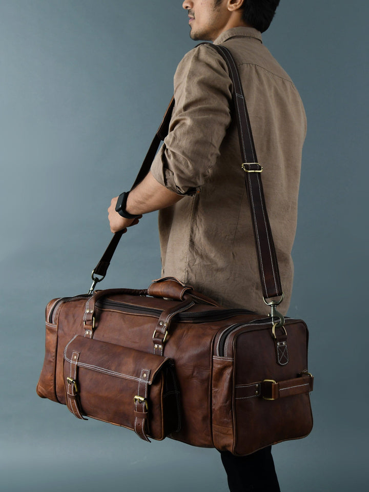 Brown leather weekender duffle bag worn on shoulder, long strap and end pockets