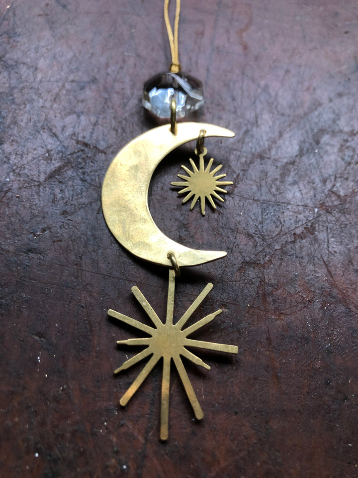 Gold crescent moon ornament with two hanging sunburst charms and clear crystal bead