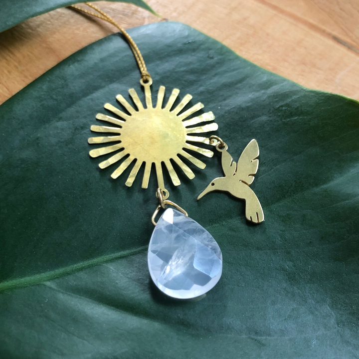 Gold-tone hummingbird ornament with sunburst charm and teardrop rose quartz pendant