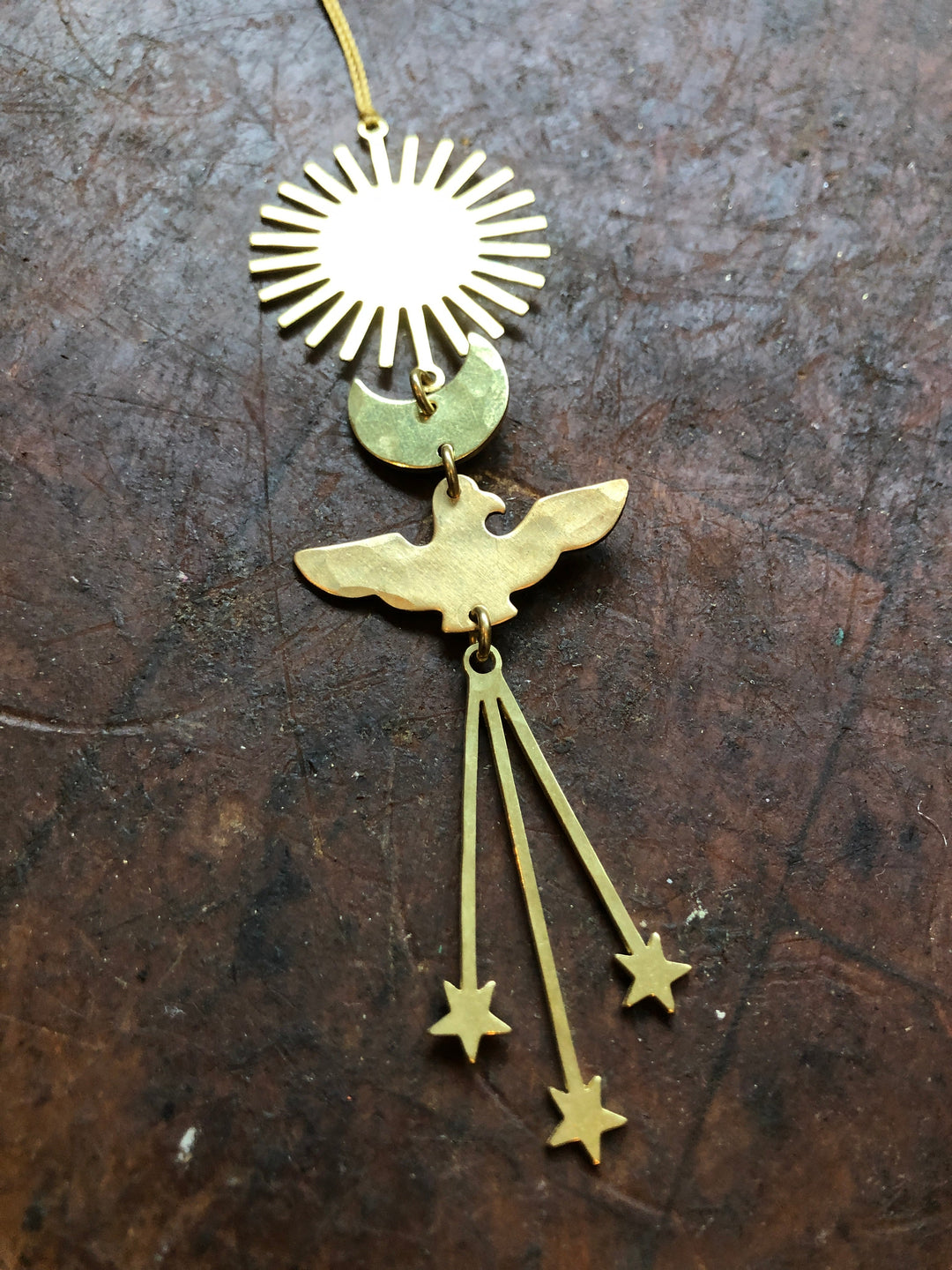 Gold angel ornament with circular sunburst, wings, and hanging star drops on cord