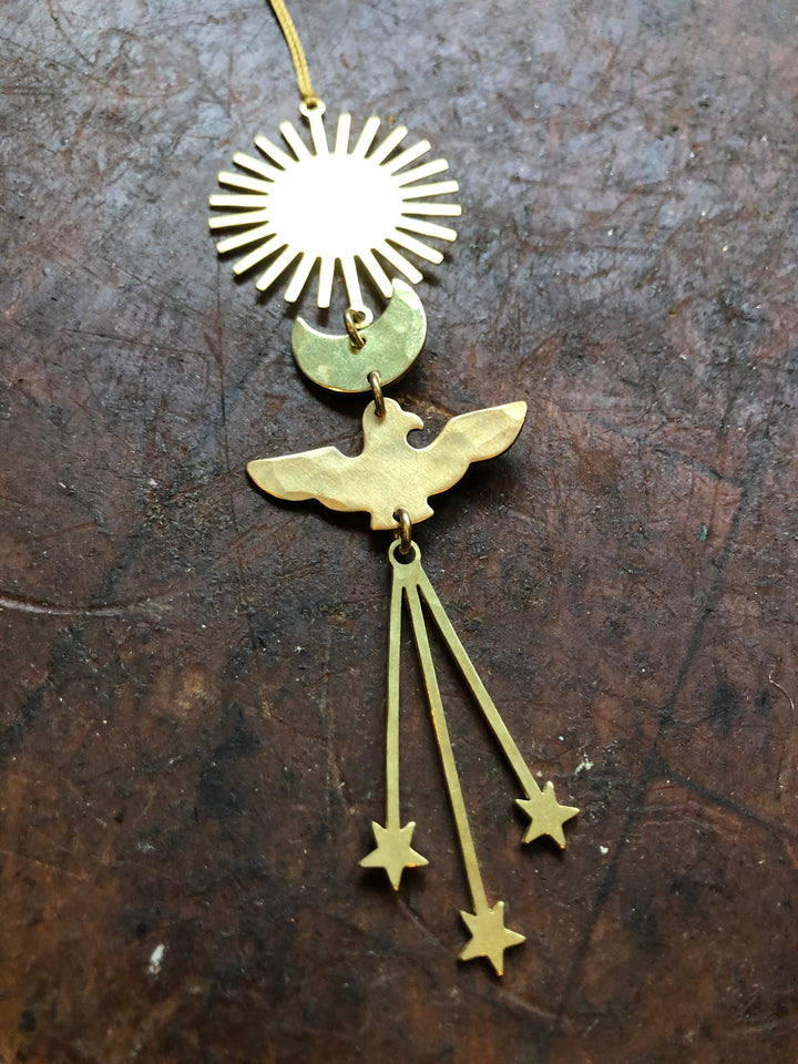 Gold angel ornament with circular sunburst, wings, and hanging star drops on cord