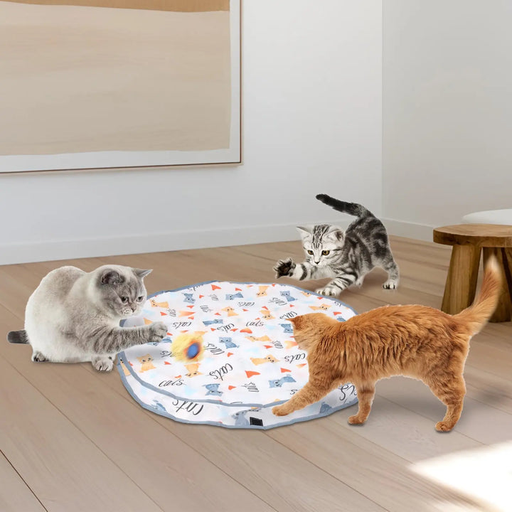 Cats playing around a round fabric interactive mat with blue ball