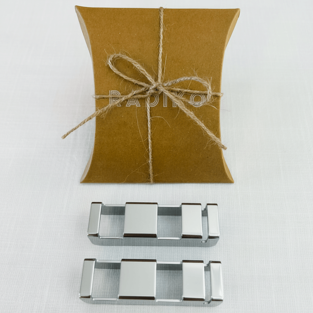 Two polished stainless steel flatware rest clips, shown side by side