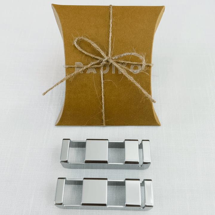 Two polished stainless steel flatware rest clips, shown side by side