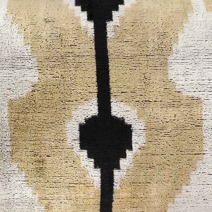Silk velvet ikat pillow close-up with textured beige and white shapes, black vertical bar
