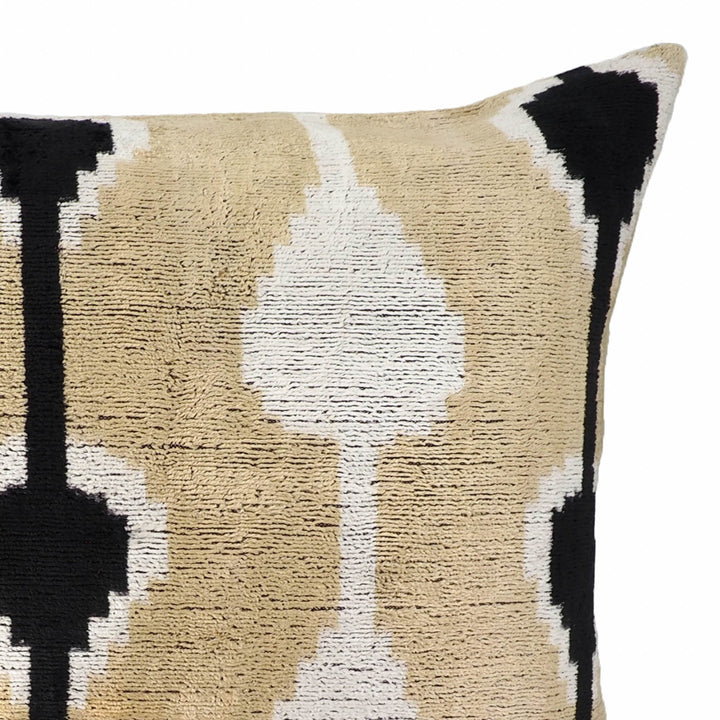 Silk velvet ikat pillow close-up showing white oval center, beige background, black corner