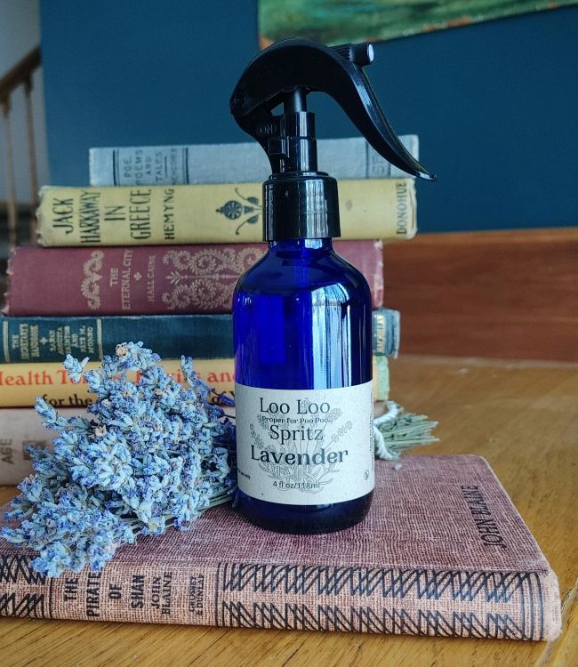 Deodorizing bathroom spray bottle in blue glass with black trigger, Lavender scent label.
