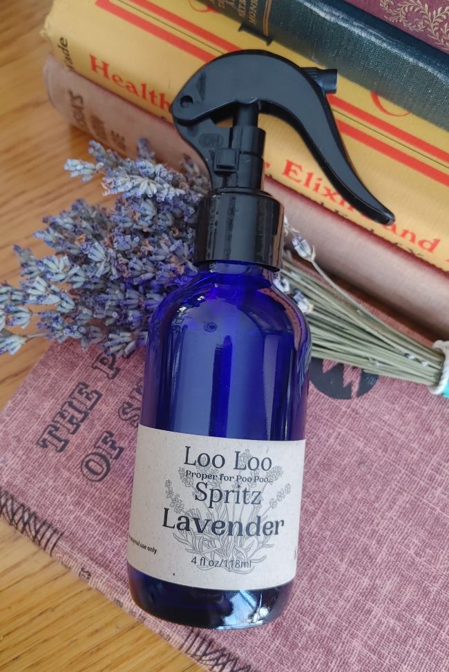 Deodorizing bathroom spray bottle in blue glass with black trigger, Lavender scent label.