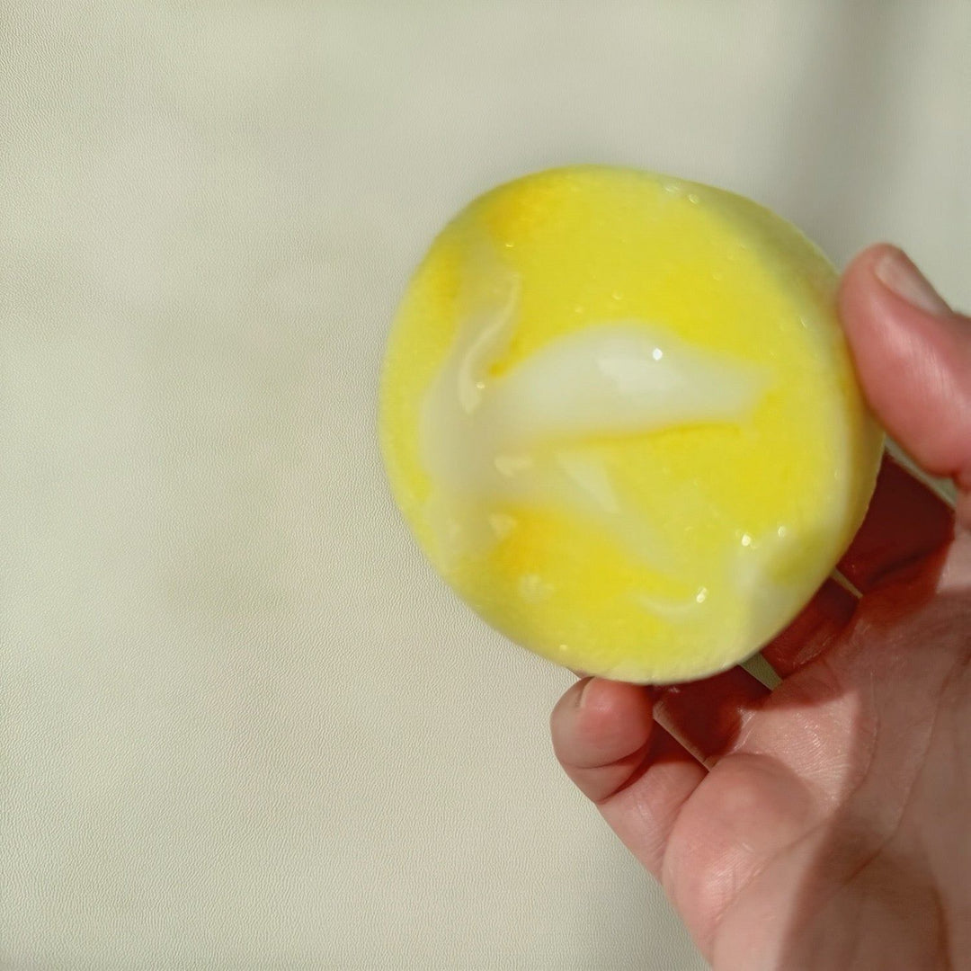 Hand holding yellow sponge with creamy cleaner suds