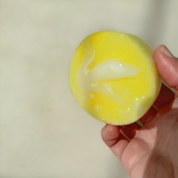 Hand holding yellow sponge with creamy cleaner suds
