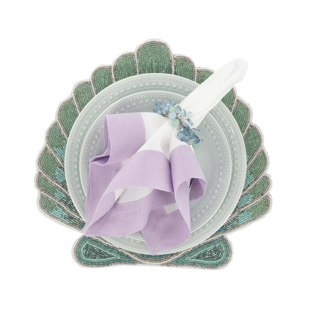 Lilac linen napkins with double-sided border, folded over a dinner plate setting