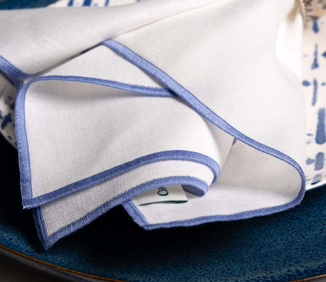 Close-up of white linen napkin with blue stitched border and clean hem